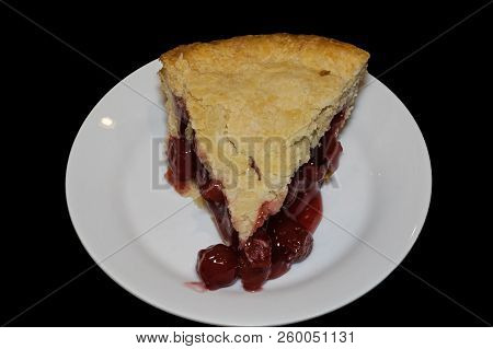 Slice Of Double Crusted Cherry Pie On Black Background. Traditionally, Cherry Pie Is Made With Tart 