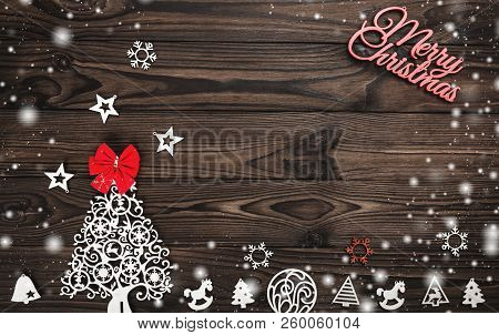 View From Above Of A Merry Christmas Inscription And Handmade Tree Toys And Red Bow On Wooden Backgr