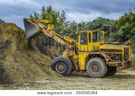 Wheel Loader Excavator With Backhoe Unloading Sand At Eathmoving Works In Construction Site Quarry