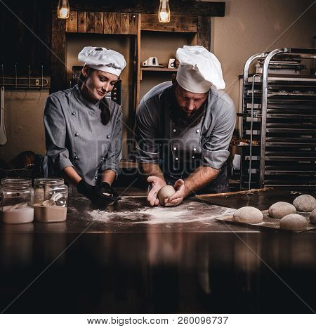 Chef Teaching His Assistant To Bake The Bread In A Bakery.