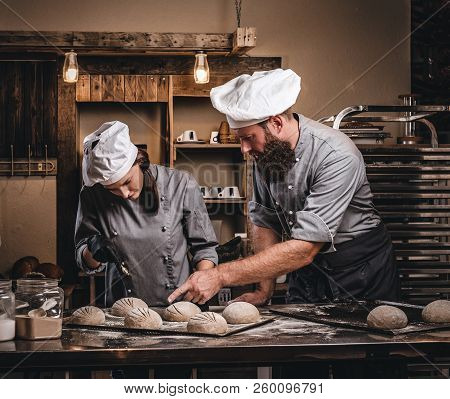 Chef Teaching His Assistant To Bake The Bread In A Bakery.