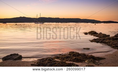Landscape With A Sailboat Sailing At Sunset On The Shores Of An Island Galicia, Spain