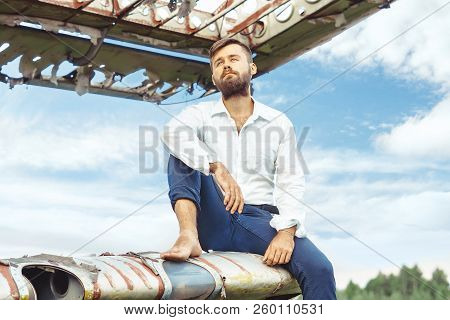 A Man In A Shirt Sitting On The Wing Of An Old Plane