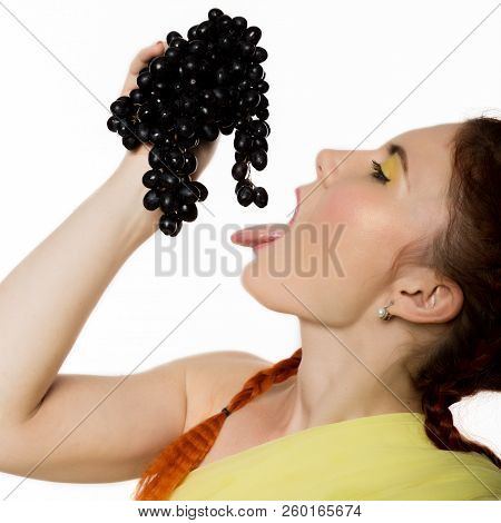 Beautiful Redhead Woman Is Eating Black Grapes. Concept Of Healthy Eating