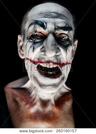 Bloody Halloween Theme: The Crazy Smiling Maniak Face On Dark Studio Background