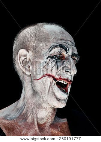 Bloody Halloween Theme: The Crazy Smiling Maniak Face On Dark Studio Background