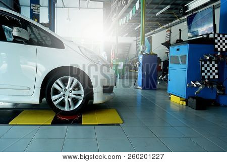 The White Car Awaiting On Position During Wheel Alignment At The Car Repair Shop