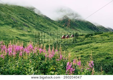 Abandoned Red Cabins Sit In The Green Lush Mountains Of Alaska’s Hatcher Pass Near Independence Mine
