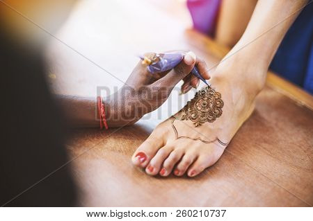The Indian Henna Artist Drawing The Tattoo Art (mehndi) On The Women Foot On The Indian Wedding Day