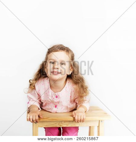 Cute Little Child Sitting On The Chair And Smiling. Wearing Pink Clothes