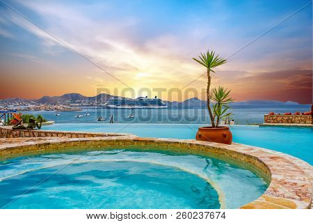 A Luxury Cruise Ship Anchored Across The Bay From A Tropical Swimming Pool