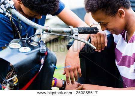Close-up ofsmiling male friends looking at old motorbike