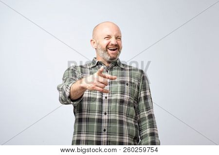 Mock Or Bad Joke Concept. Mature Man Pointing Finger And Toothy Smile.