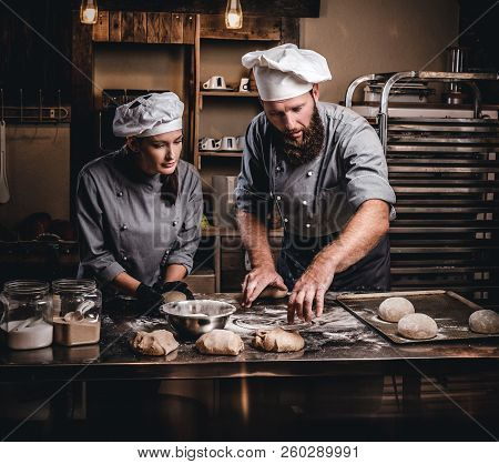 Chef Teaching His Assistant To Bake The Bread In A Bakery.