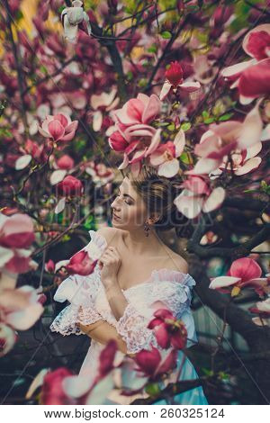 Young Beautiful Girl Among Pink Magnolia Flowers.