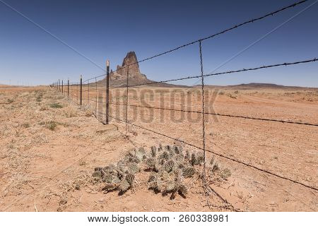 Agathla Peak Seen From Behind A Barbed Wire Fence, Monument Valley, Kayenta County, Arizona, Usa.