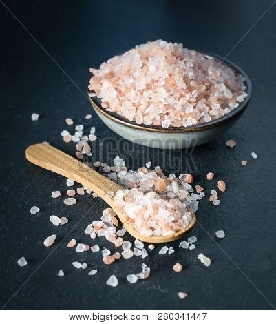 Pink Himalayan Salt On Wooden Spoon And Bowl On Black Stone Background