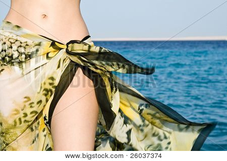 หน้าท้องของหญิงในผ้าคลุมไหล่ผ้าชายหาด