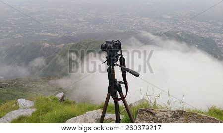 camera on a tripod in the background of a valley above the clouds