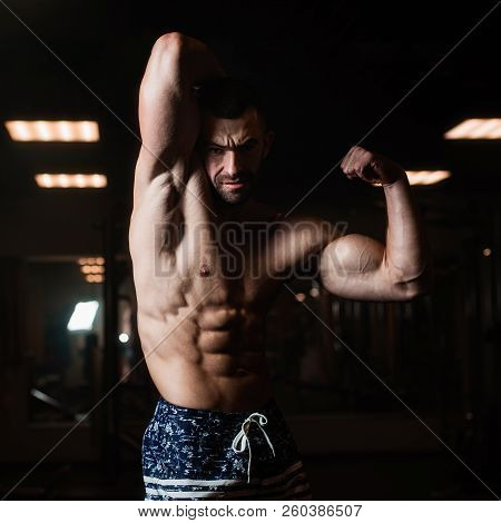 Strong Fitness Man Demonstrates His Bicep In The Gym. The Concept Of A Healthy Lifestyle