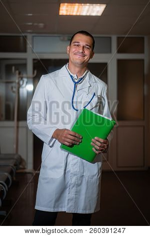 Portrait Of A Beautiful Doctor In The Hospital With A Folder In His Hands