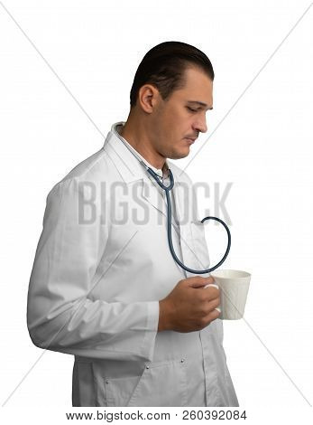 Young Male Doctor With A Mug In His Hand Looks Thoughtfully