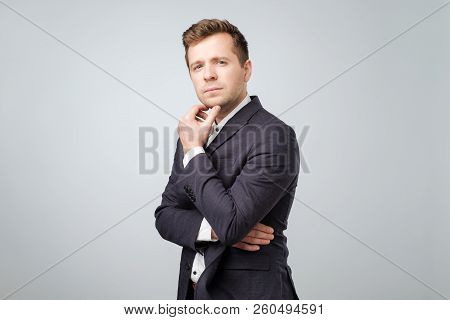 Handsome Young Businessman Thinking Abour His Job Standing Against Grey Background