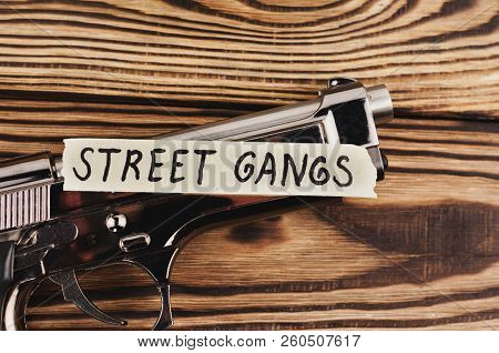 Inscription Street Gangs On Torn Paper And Glossy Pistol On Old Rustic Wooden Weathered Planks