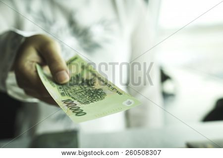Close Up Of Asian Woman's Hand Holding Vietnam Bank Note Make Payment At Shop Or Supermarket. Asia C