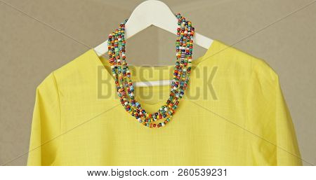 Bright Beads Of Murano Glass Hang On The Background Of A Yellow Summer Dress. Summer Jewelry, Summer