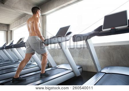 Muscular Bodybuilder Guy Exercise Running On Treadmill In The Gym .sport Young Fitness Man Shirtless