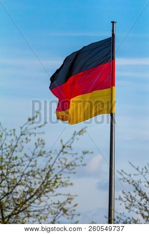 Federal Republic Of Germany, German National Flag Waving On The Blue Sky Background