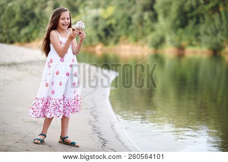 girl playing with a toy sailing ship by the river
