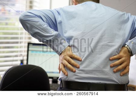 Close-up View Of A Office Worker Man With Pain In Kidneys. Young Male With Back Ache Clasping Her Ha