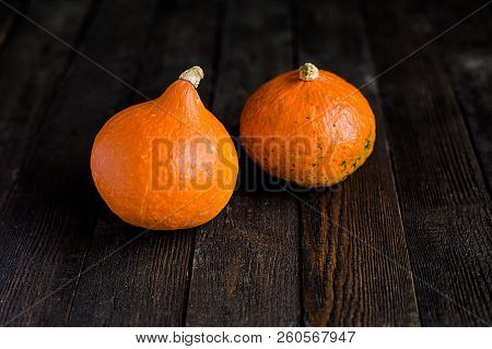Small Orange Pumpkins On The Dark Wooden Table, Autumn Concept, Harrvest Time. Copy Space.