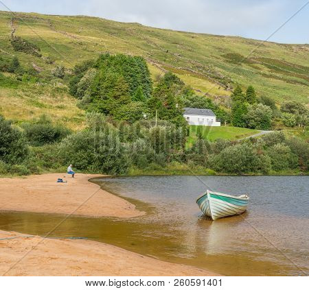 Lough Nafooey, Ireland - August 22, 2018: A Lone Fisherman And A Boat On The Beach At Lough Nafooey 