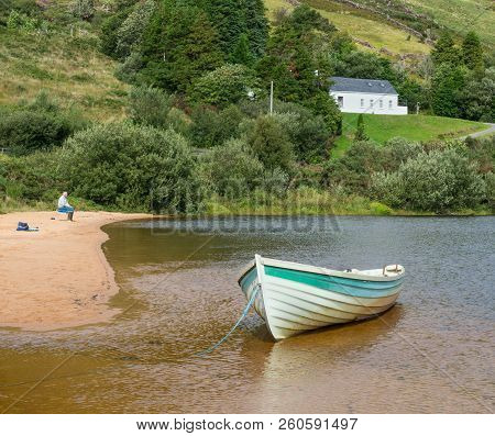 Lough Nafooey, Ireland - August 22, 2018: A Lone Fisherman And A Boat On The Beach At Lough Nafooey 