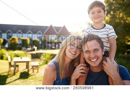 Portrait Of Family With Father Giving Son Ride On Shoulders In Garden Of Summer Pub