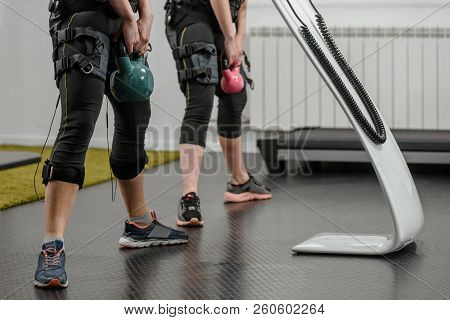 Closeup Of Two Women In Ems Suits Doing Exercises With Kettlebell