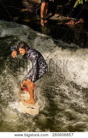 Munich, Germany - Sept 8, 2018: A Man Surfing In The Waves Of The Eisbach River In Downtown Of Munic