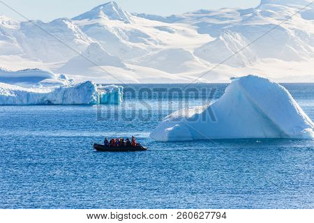 Boat Full Of Tourists Passing By The Huge Icebergs In The Bay Near Cuverville Island, Antarctic Peni