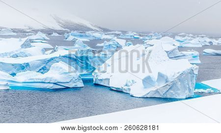 Cold Still Waters Of Antarctic Sea Lagoon With Drifting Huge Blue Icebergs, Port Charcot, Booth Isla
