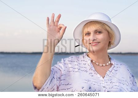 Happy Retired Elderly Lady In White Hat Shows Okey Geste