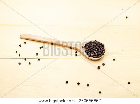 The Wooden Spooon With Black Pepper Seed,put On Yellow Wooden Timber Board,blurry Light Around.