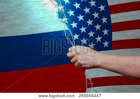 Trade War Between Usa And Russia Concept: Barbed Wire In A Hand Between American And Ryssian Flags