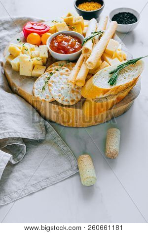 Cheese Board With Tomatoes, Jam, Baguette, Bread Sticks And Crackers