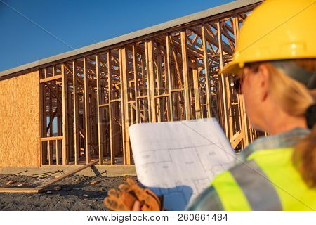 Female Construciton Worker with House Plans at Construciton Site.