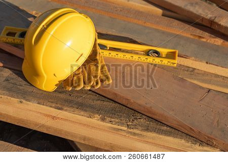 Abstract of Constrcution Hard Hat, Gloves and Level Resting on Wood Planks.