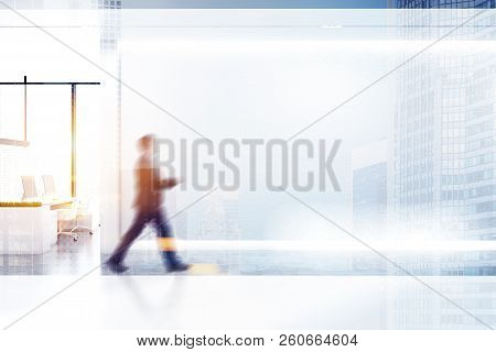 Businessman Walking In Minimalistic Office With White Walls, Concrete Floor With Rows Of White Table