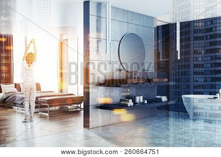 Woman In Pajamas Standing In A Master Bedroom Interior With Adjoined Bathroom. Luxury Dwelling Conce